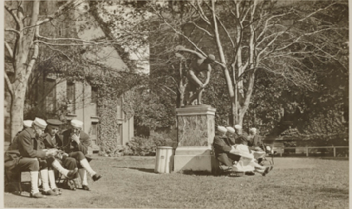 Men wearing uniforms gather in two small groups on campus.